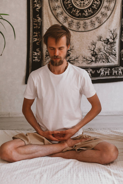 A vertical shot of a male meditating and doing yoga at home - Fotoğraf, Görsel