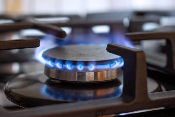 A burning gas burner on the kitchen stove. The use of natural gas for cooking. - Photo, Image