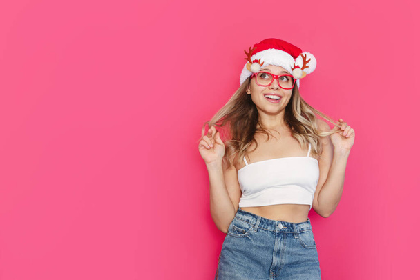joyful woman posing in santa hat and funny eyeglasses - Foto, imagen
