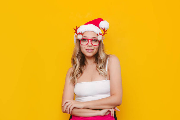 photo of a young woman wearing santa hat  posing over yellow background. - Photo, Image