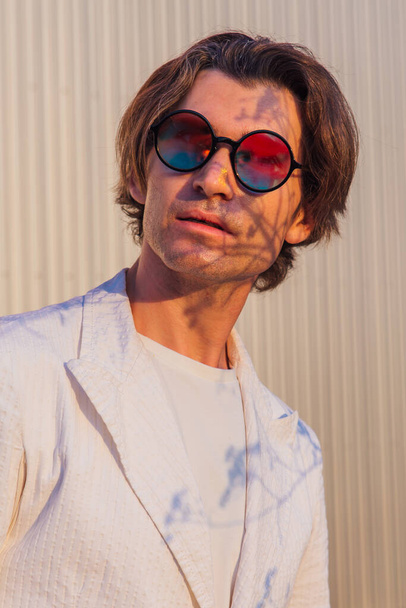 Close up portrait of a handsome man with round hippie sunglasses during sunset - Фото, зображення