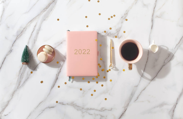 Flat lay composition with New Years decoration, coral colored 2022 diary book and coffee cup and Macaron cookie - Foto, imagen