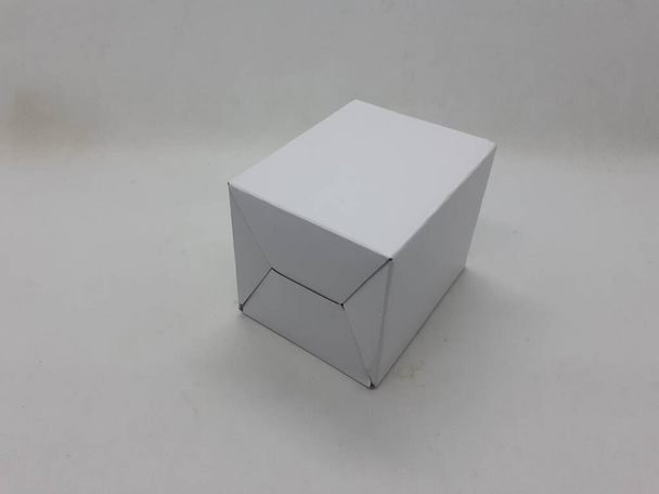 Ένα μικρό λευκό αναδιπλούμενο χάρτινο κουτί σε λευκό φόντο απομόνωσης - Φωτογραφία, εικόνα