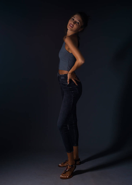 Stylish fashion girl posing in trendy clothes against black background - Фото, зображення