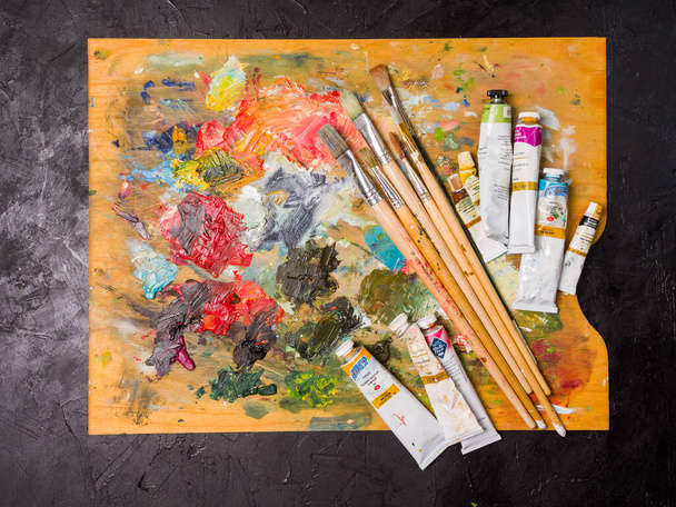 Krasnoyarsk. Russia - August 13, 2021: Artist's palette. Oil art paints extruded onto a wooden palette. Tubes and brushes lie on a colorful board - Foto, immagini