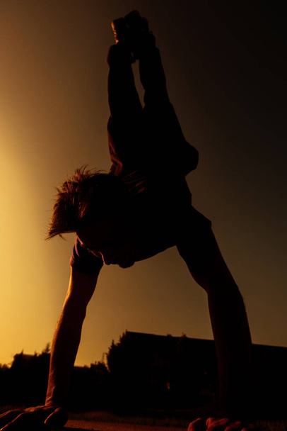 Parkour moves uitgevoerd door een acrobatische jongen in de lokale skate speeltuin - Foto, afbeelding