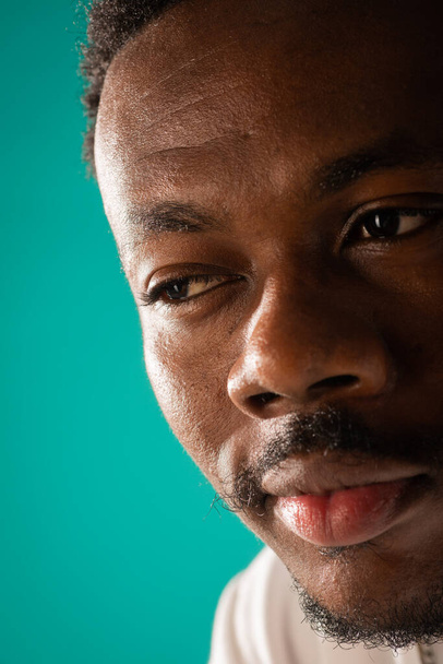 close-up portret van Afrikaanse zwarte man poseren op blauwe achtergrond, in studio - Foto, afbeelding