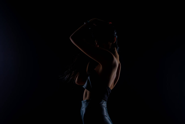Silhouet van aantrekkelijk meisje poseert in de studio terwijl speels met haar haar - Foto, afbeelding