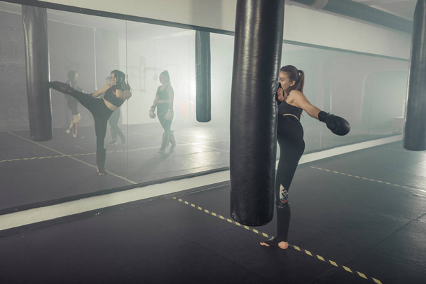 Young adult sexy woman doing back leg high kick during kickboxing. - Foto, afbeelding
