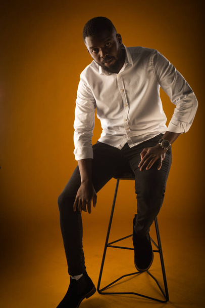 Handsome black guy is posing while sitting on the high chair - Fotó, kép