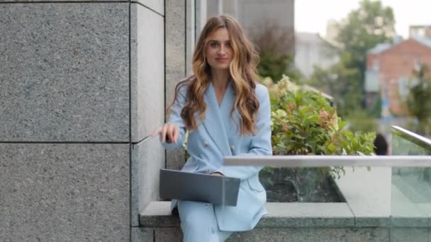 Beautiful successful caucasian millennial business woman student boss manager employee female sits with laptop on terrace balcony in office looking at camera shows ok sign okay gesture success victory - Footage, Video