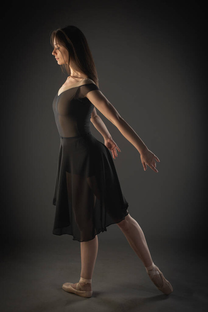 Piękna balerina pozuje z wdziękiem w studio na szarym tle - Zdjęcie, obraz
