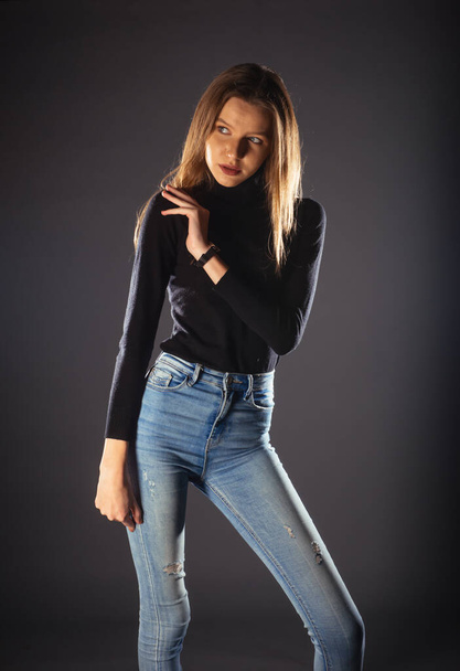 A fashionable young woman in black roll neck posing isolated on a dark background - Foto, afbeelding