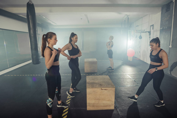 Four sportswomen are training glutes with multifunctional training in a sports club - Zdjęcie, obraz
