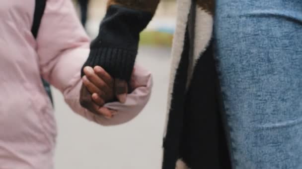 Κοντινό πλάνο αγνώριστη αφροαμερικάνικη μαύρη μητέρα γυναίκα και κόρη παιδί παιδί γιος μωρό περπάτημα έξω κρατώντας τα χέρια μαζί στο δρόμο με τα πόδια διακοπές σε εξωτερικούς χώρους. Οικογενειακές σχέσεις έννοια - Πλάνα, βίντεο