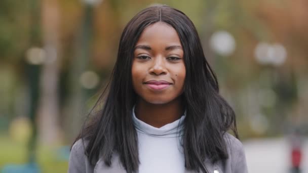 Elölnézet közelről vegyes verseny fiatal nő gyönyörű modell női arc fekete bőr afro tini hölgy nézi kamera mosolyog a szabadban. Afrikai amerikai lány mosoly egészséges fehér fogak a parkban - Felvétel, videó