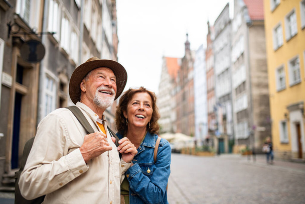 Portrait of happy senior couple tourists outdoors in historic town - Photo, image
