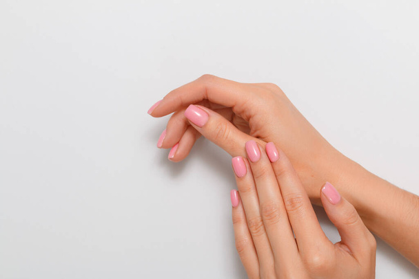 Beautiful hands of a woman with manicure isolated on a light gray background. Skin care concept. Close-up. - Fotó, kép