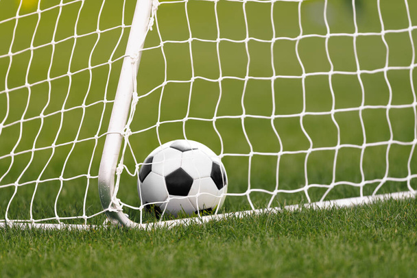 Football Ball in a Goal. Soccer Ball Lying in Grass. Football Equipement. White Soccer Goal and Net - Fotó, kép