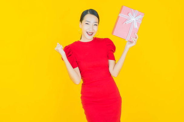 Portrait beautiful young asian woman smile with red gift box on color background - Photo, Image