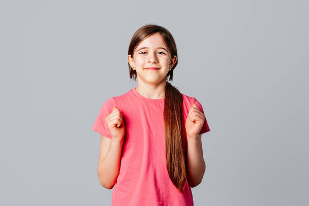 Holidays, events and emotions concept. Happy smiling young girl winning and screaming from joy, achieve goal, celebrating victory, making fist pumps, standing over grey background - Photo, image