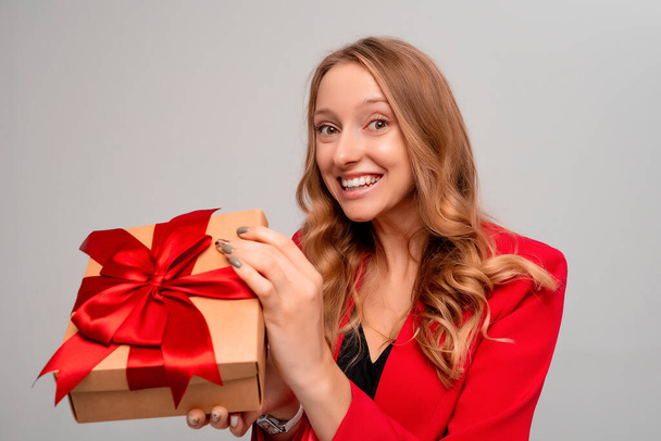 Beautiful young woman holding in hands unboxed present and looking at camera with smiling broadly. Female person enjoying long-awaited birthday present, dreams come true. Studio shot gray background - Photo, image