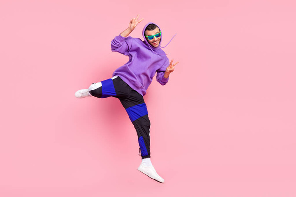 Full body photo of funny young brunet guy jump wear eyewear hoodie pants shoes isolated on pink background - Фото, зображення