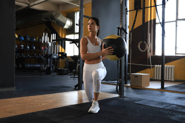 Fit and muscular woman exercising with medicine ball at gym - 写真・画像