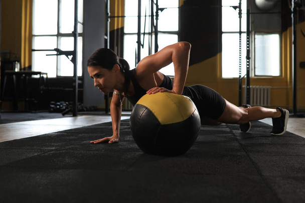 Fit and muscular woman exercising with medicine ball at gym - Photo, image