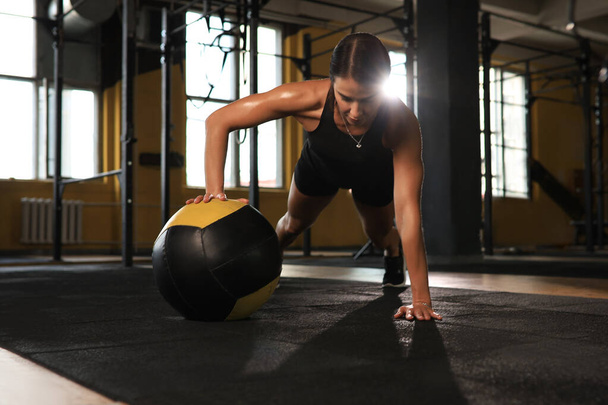 Fit and muscular woman exercising with medicine ball at gym - 写真・画像