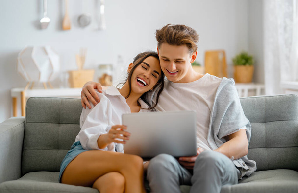 Young couple is using laptop. Woman and man having fun staying at home. - Foto, Imagen