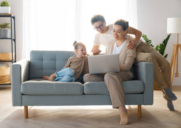 Happy loving family. Young mother, father and daughter using laptop. Funny mom, dad and lovely child are having fun staying at home. - Φωτογραφία, εικόνα