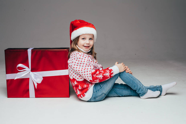 Niño encantador en sombrero de Santa junto a regalo de Navidad. - Foto, Imagen