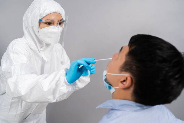 doctor with PPE suit test coronavirus(covid-19) to young man by nasal swab  - Φωτογραφία, εικόνα