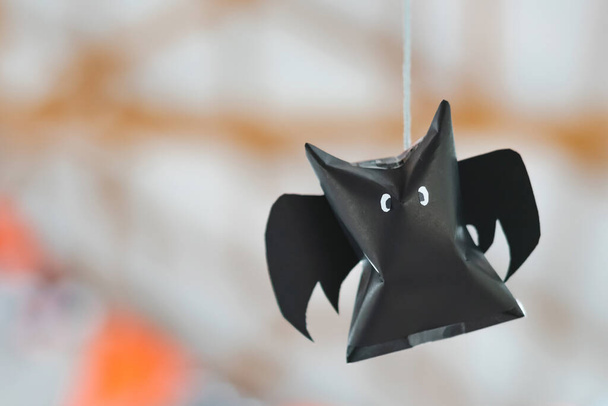 Bâton origami en papier noir accroché à une corde pour les décorations d'Halloween. Papier sombre fantôme Halloween fête concept origami chauve-souris en papier. La figure de chauve-souris en papier noir volant au-dessus de la pièce. Espace pour le texte. - Photo, image
