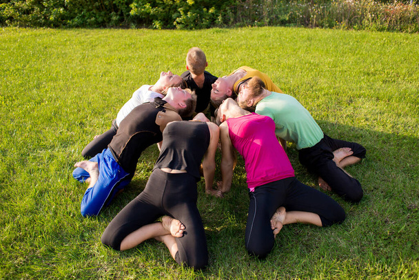 A group of people in a lotus pose on a green lawn in the park - Foto, imagen