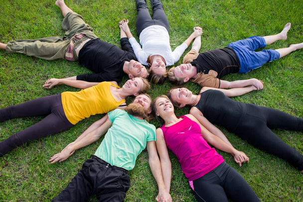 A group of people lies on a green grass in a circle - Foto, Imagen