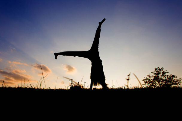 Silhouette of a yogi at sunset. Exercises for the balance. - Zdjęcie, obraz