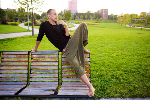 A young man is meditating on a bench in the park - Valokuva, kuva