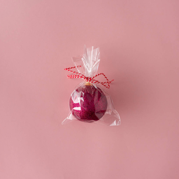 Pink Christmas bauble decoration in sachet on pastel pink background. New Year greeting card. Minimal style. Flat lay. - Foto, Imagem