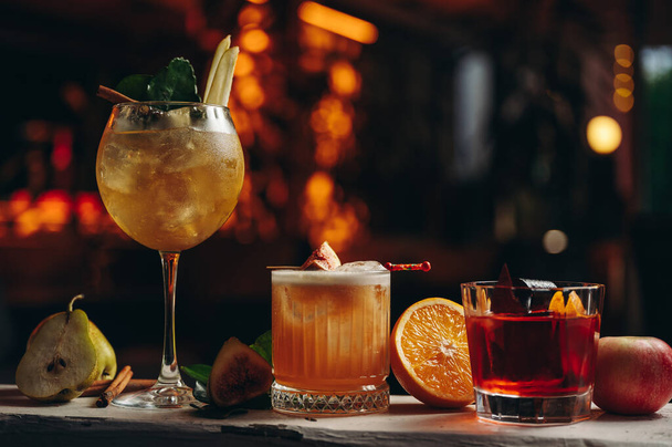 Three different beautiful cocktails in warm colors on a flower background. cocktail or bar menu concept. - 写真・画像