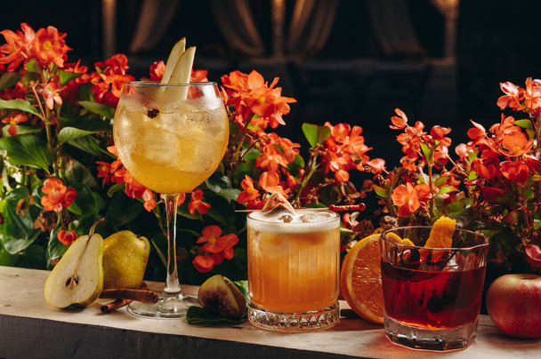 Three different beautiful cocktails in warm colors on a flower background. cocktail or bar menu concept. - Φωτογραφία, εικόνα
