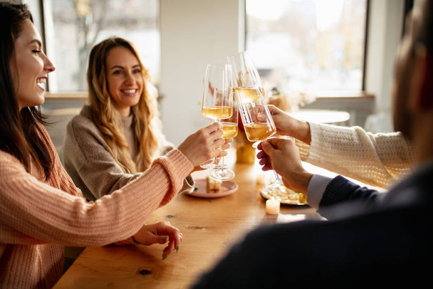 Обрезанный портрет друзей, встречающихся в кафе, пьющих белое вино с вкусной едой. Солнечный день - Фото, изображение