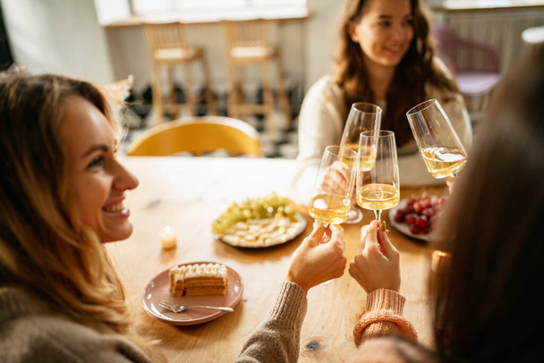 Beautiful smiling friends, women drinking delicious white wine at the meeting in restaurant - Foto, Bild