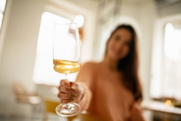 Nahaufnahme eines Glases mit köstlichem Weißwein. Lächelndes Mädchen beim Verkosten von Getränken - Foto, Bild