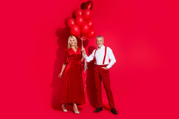 Full body photo of senior husband wife date romantic hold air balloons glamour elegant occasion isolated over red color background - Photo, image
