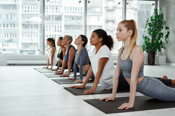 Diverse women practice yoga meditate at group training - Фото, изображение