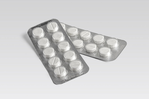 White prescription medical pills in a shiny blister pack on a light background - Foto, afbeelding