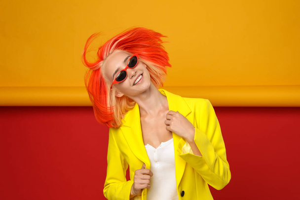 Beautiful young woman with bright dyed hair shaking head on color background - Fotoğraf, Görsel