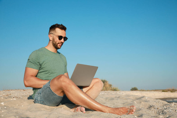 Man working with laptop on beach. Space for text - Foto, Imagen